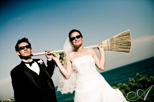 becky-and-danny-wedding-bride and groom with a broom- view of the ocean- destination wedding in Newport RI