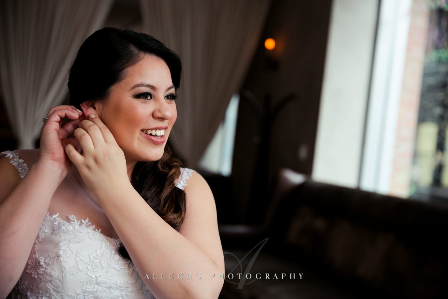 bride puts on wedding jewelry earrings -photo by allegro photography
