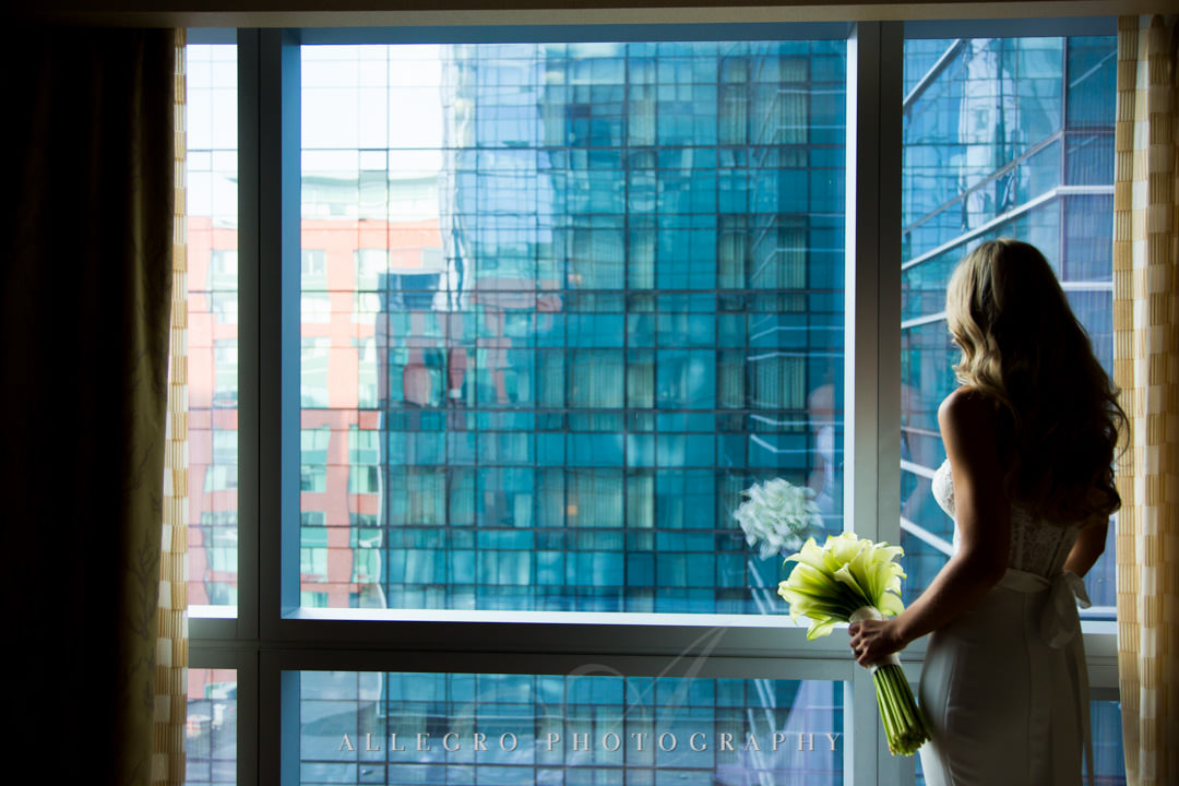 Bride stares out at Boston in hotel room