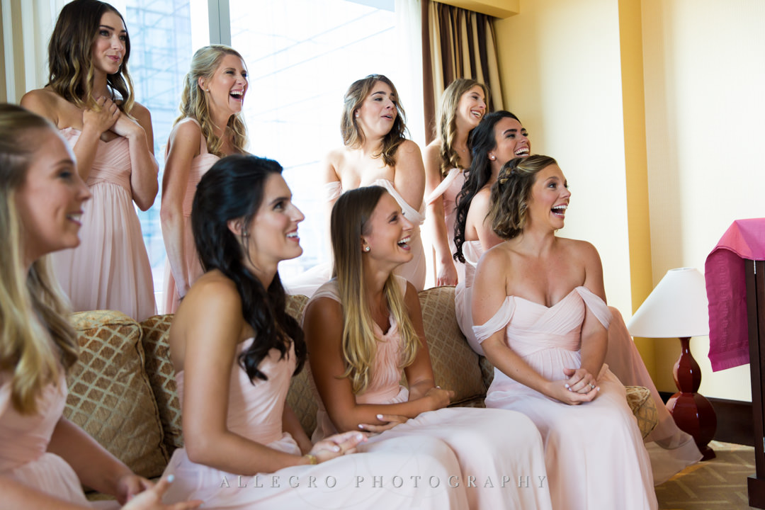 Bridesmaids smile at seeing the bride all ready