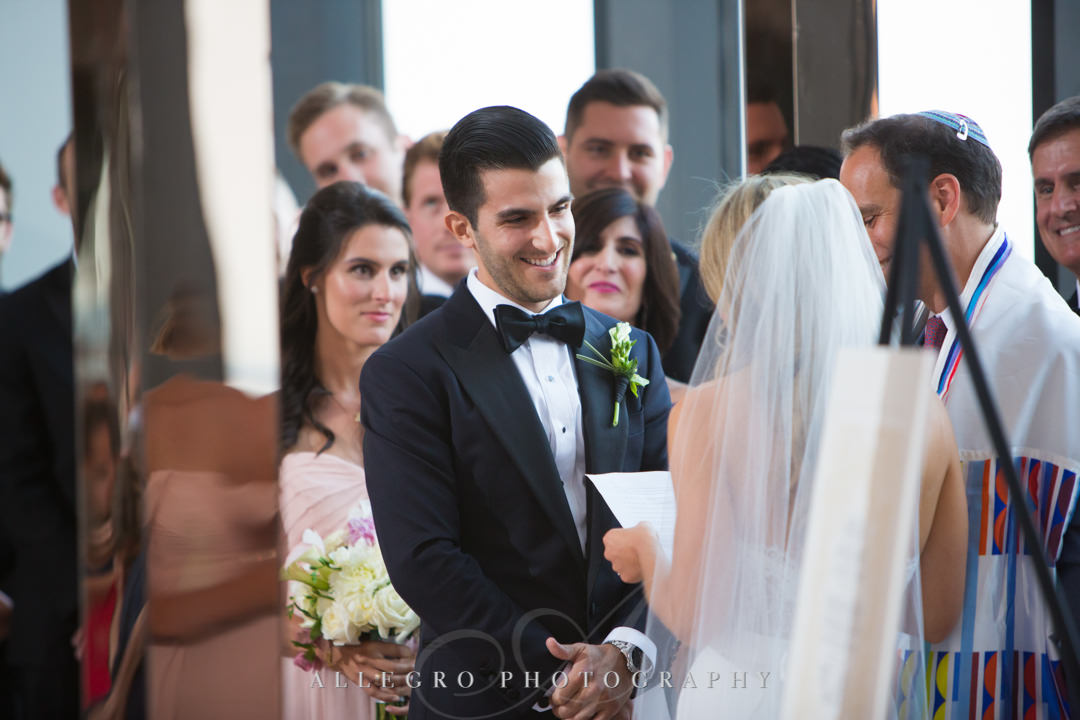 Groom smiles at bride at alter