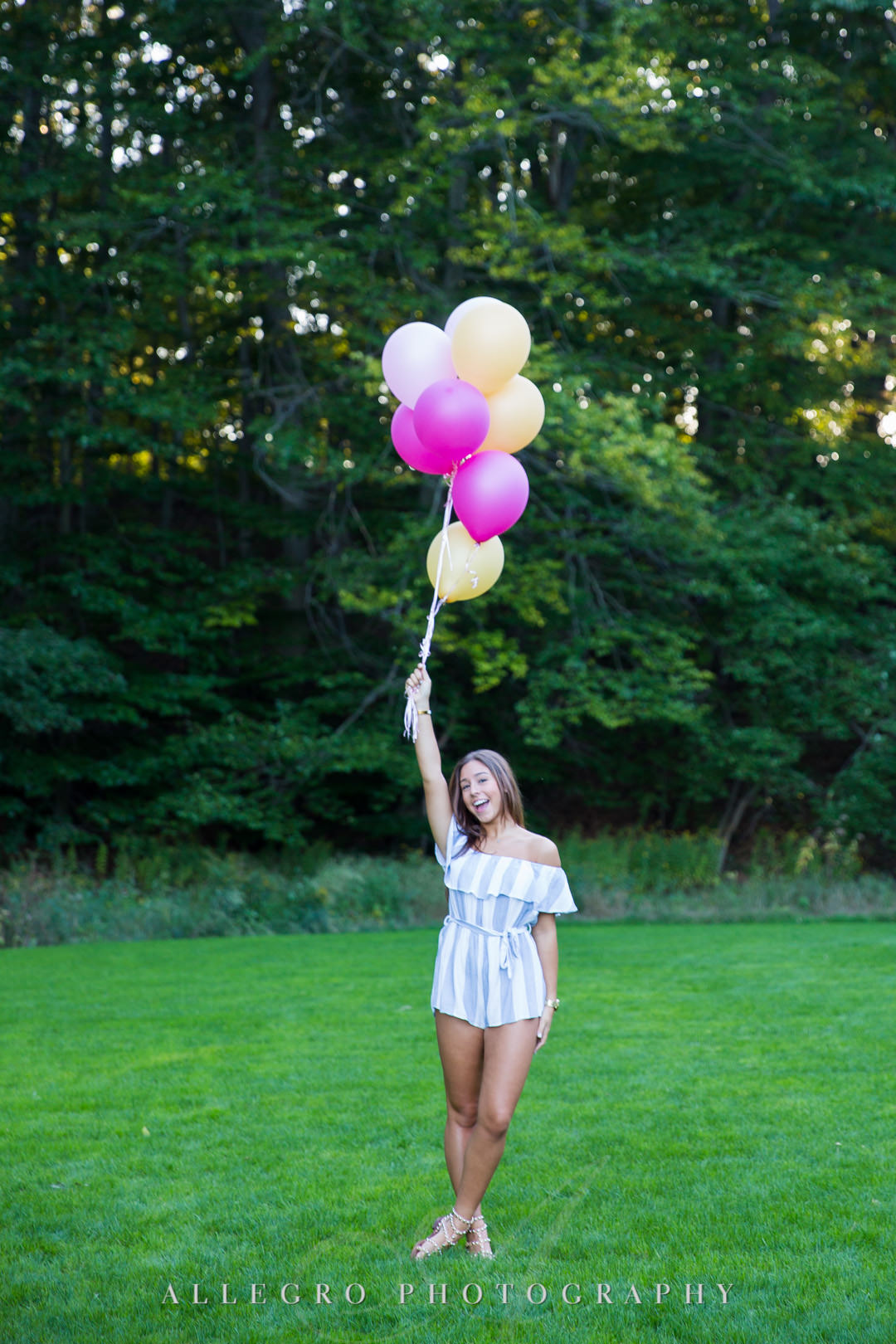 Playful senior in high school holding up balloons at Wellesley College