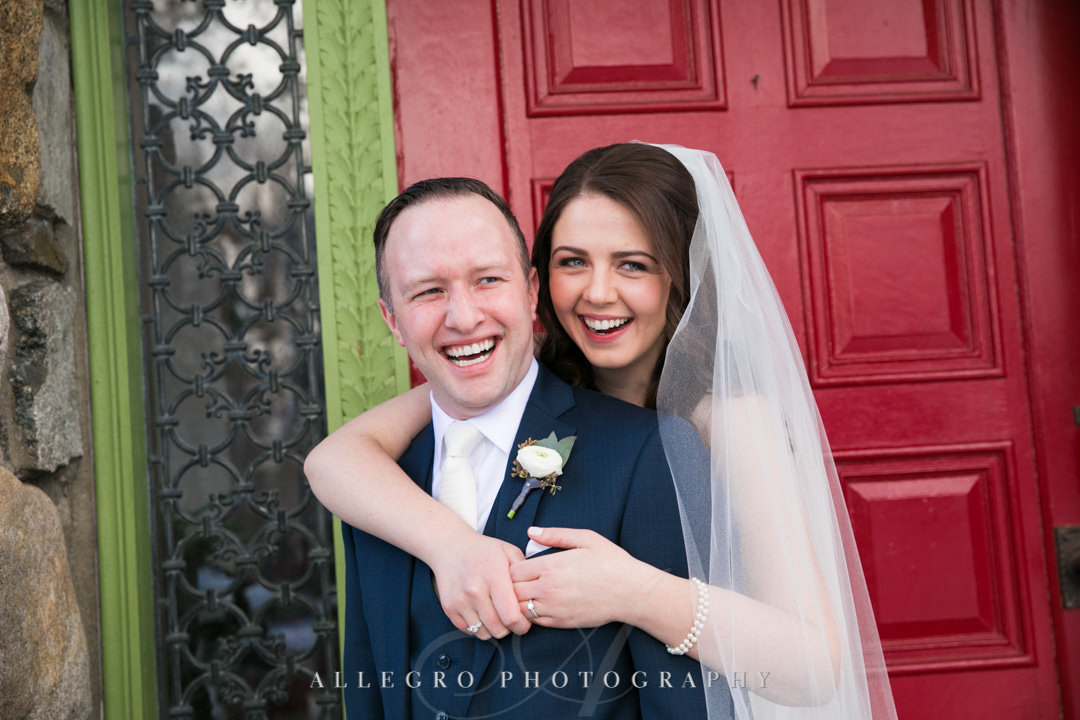 Bride and groom smile in front of bright red door