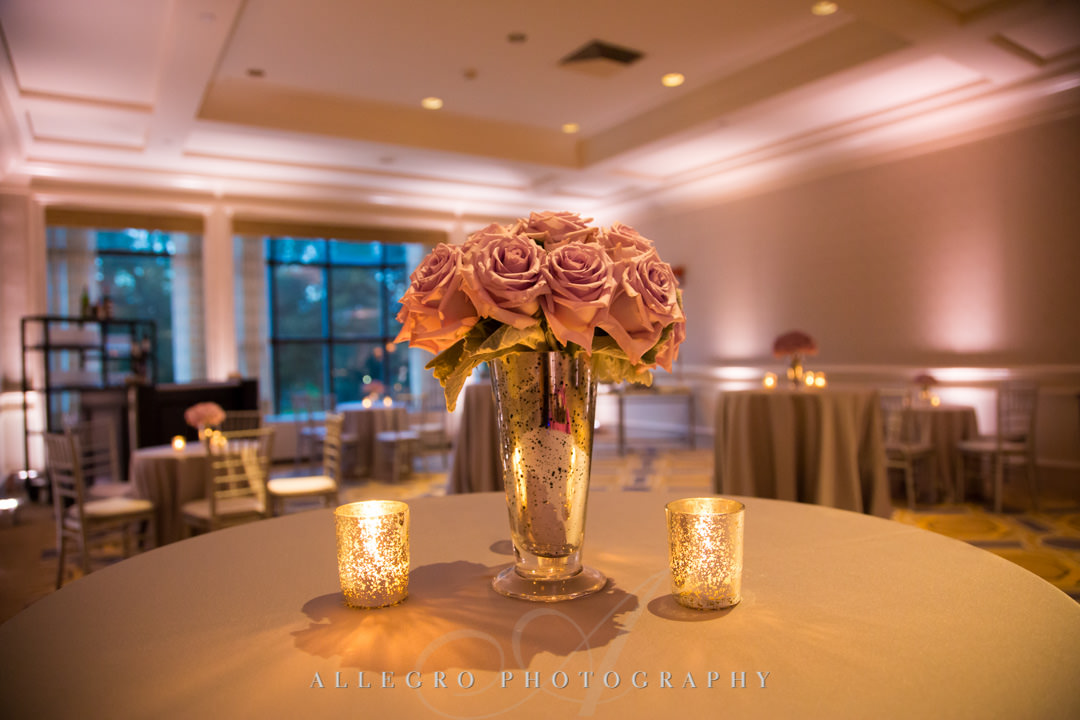 Pastel pink flowers next to two candles | Allegro Photography