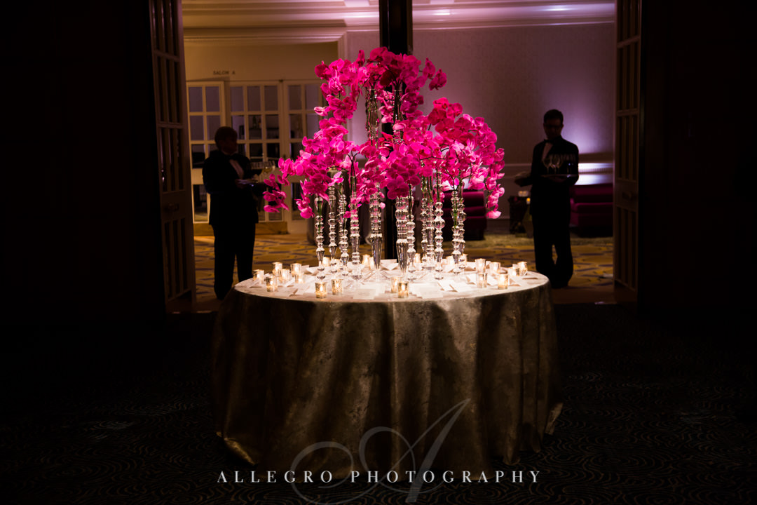 Neon pink flower arrangement surrounded by candles | Allegro Photography
