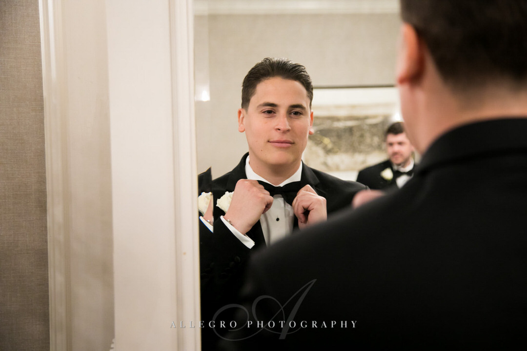 groom fixes bow tie in the mirror