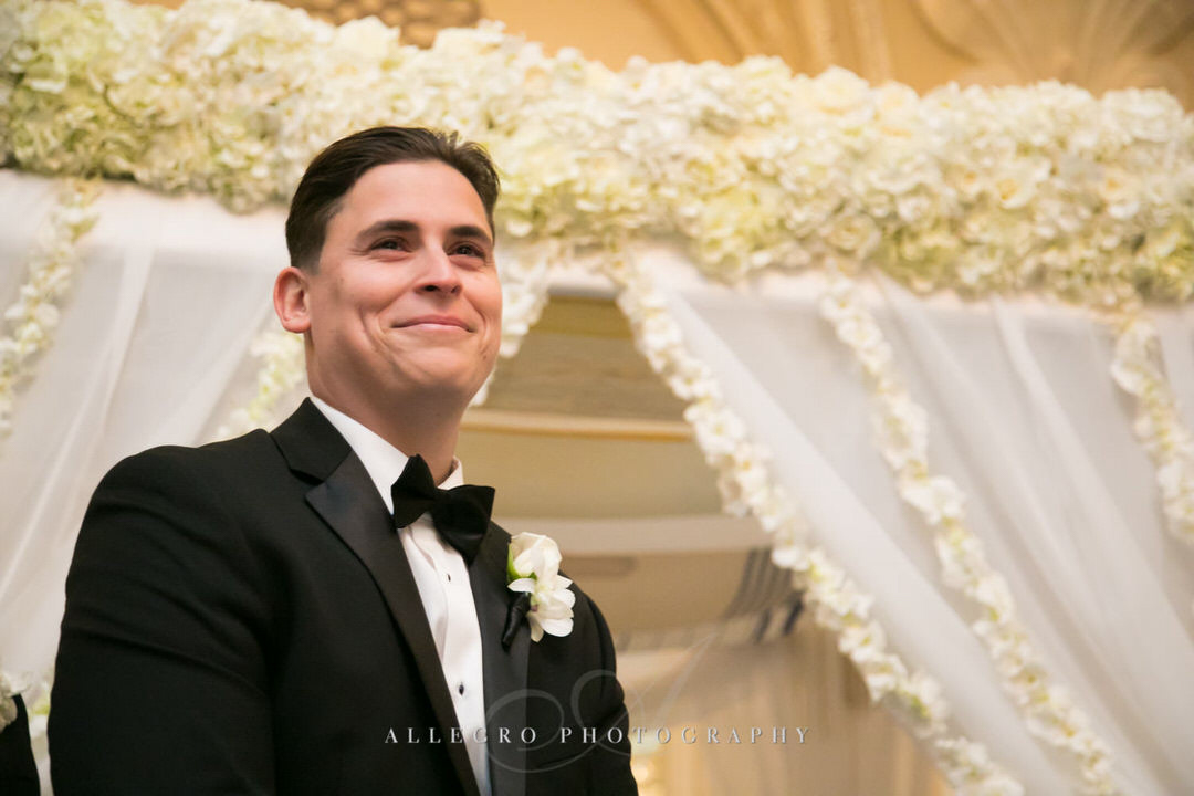 groom smiles as he watches for the bride