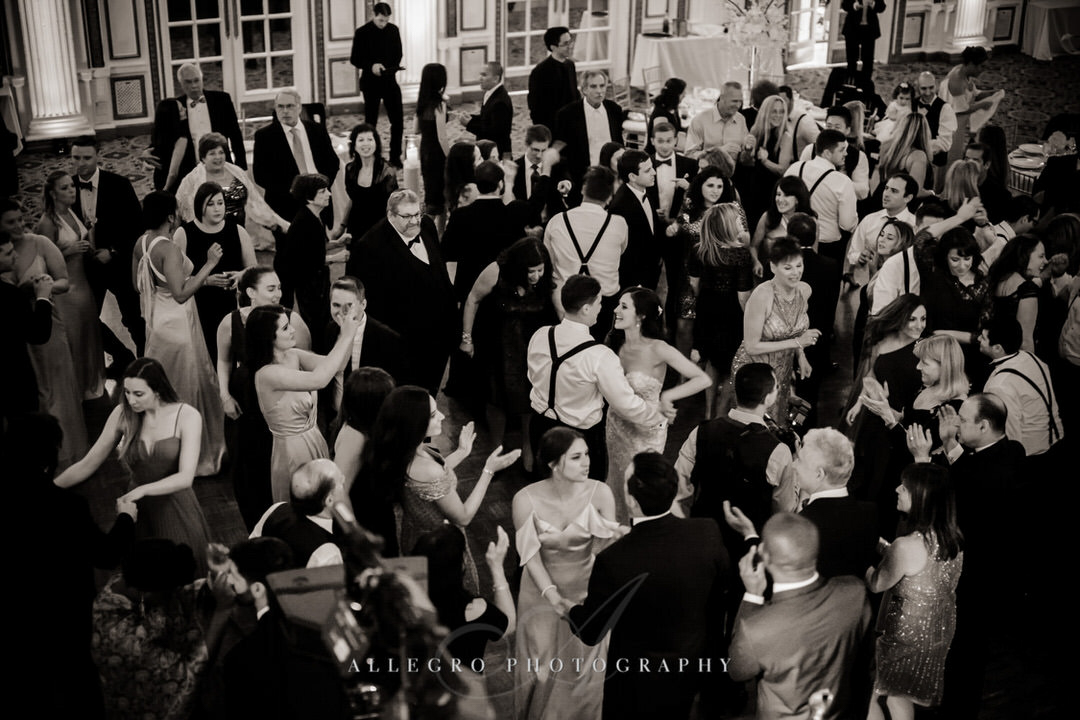 bride and groom dance together with people dancing around them