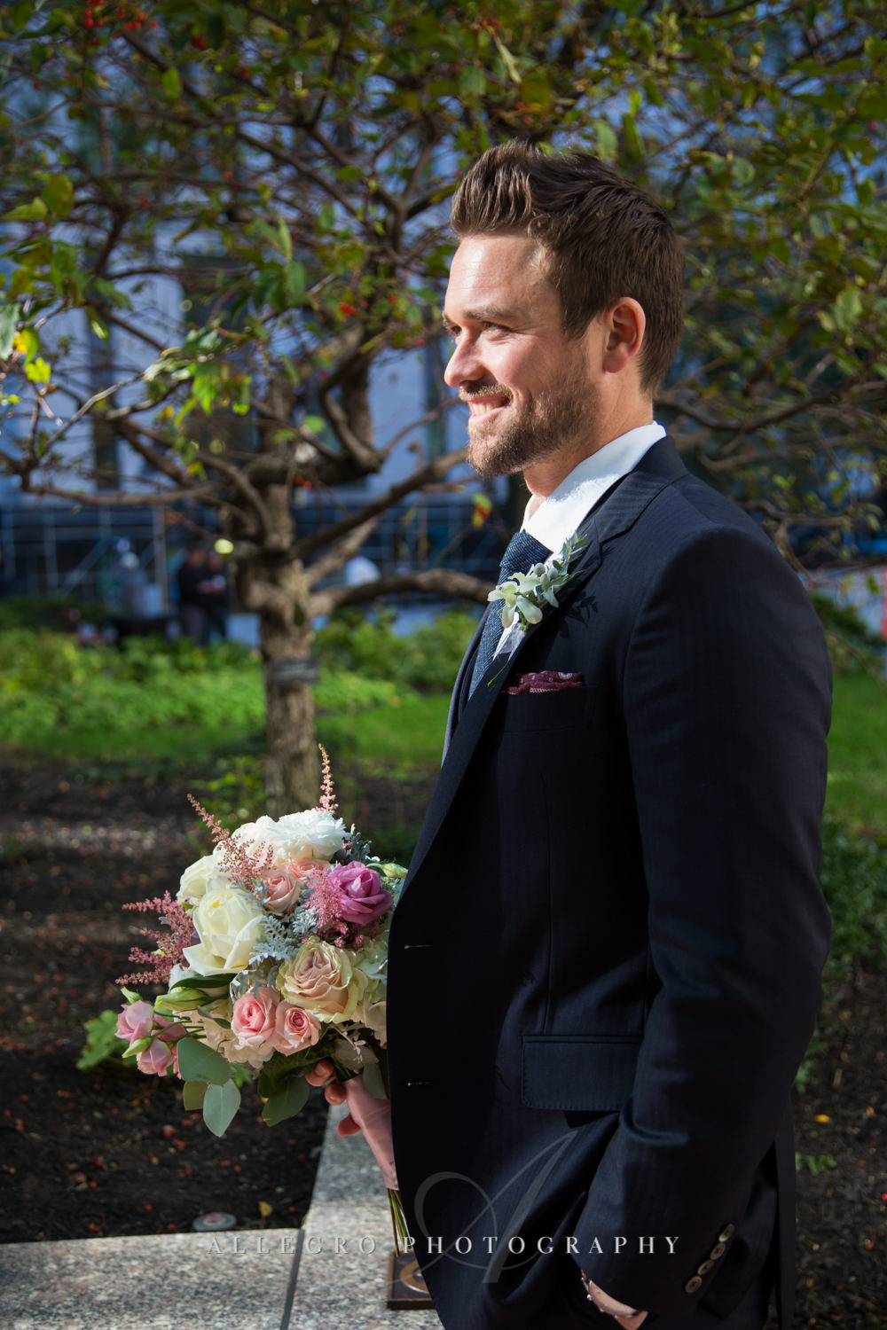 groom holds bouquet for bride