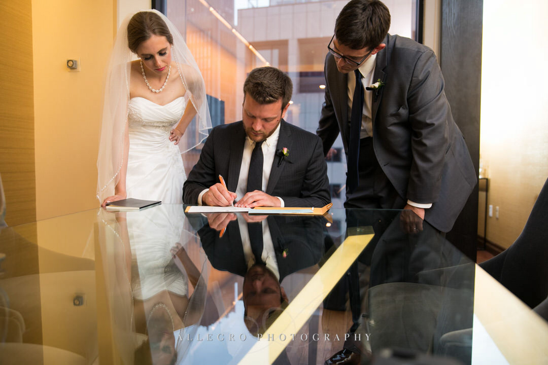 bride and groom watch as the wedding document gets signed