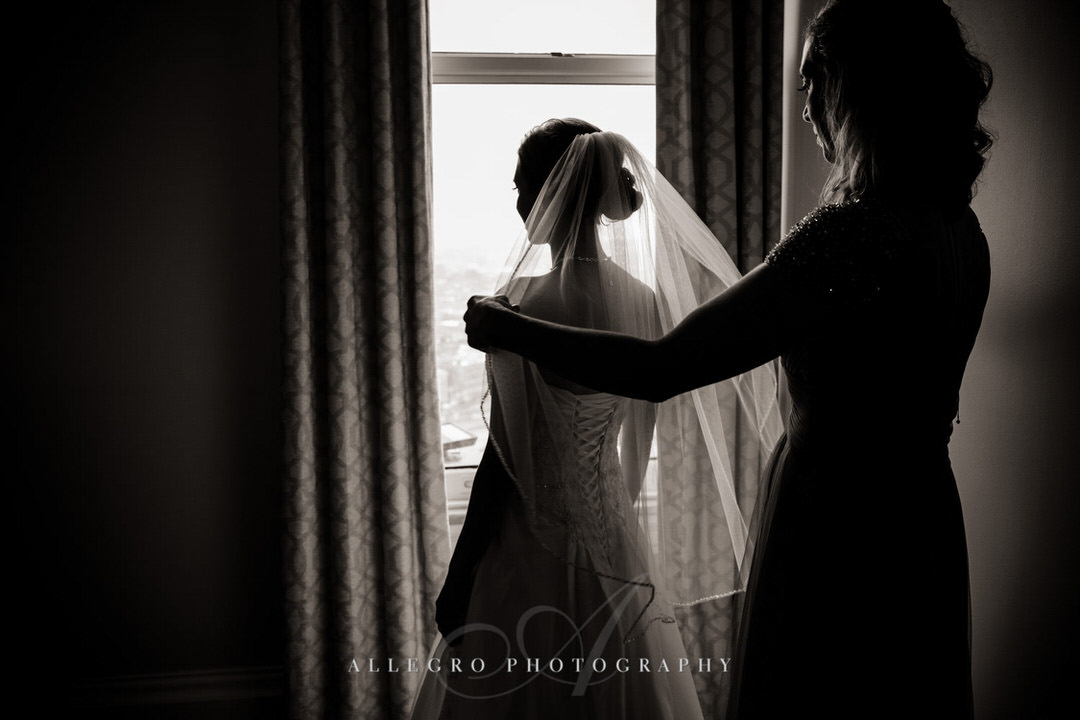 mother of the bride helps bride put on veil
